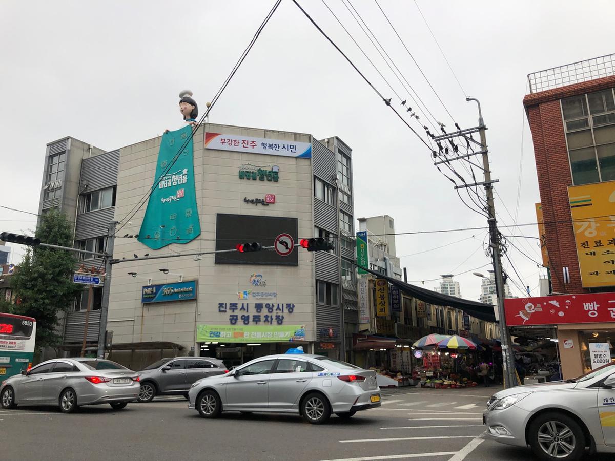 차량과 상점, 사람들이 오가는 진주 중앙시장 입구